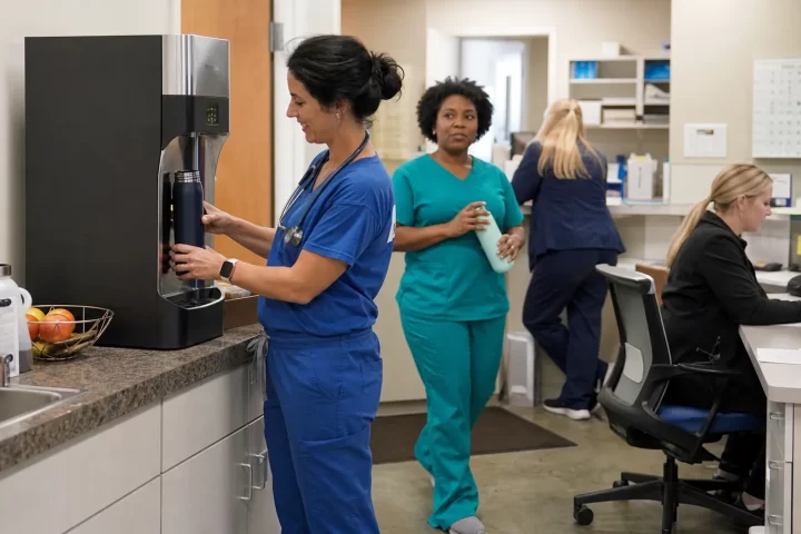 Medical practice staff using a bottleless water cooler in a working clinic break area