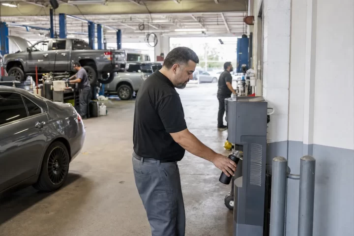 Service advisor using a commercial water cooler between an auto dealership service drive and repair shop