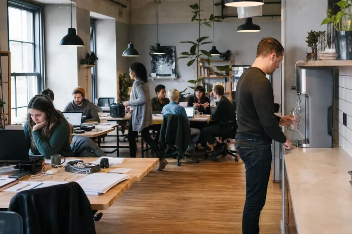 Coworking member filling a reusable bottle at a shared office water dispenser