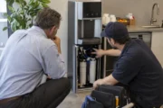 Facilities manager inspecting a bottleless office water cooler with a service technician